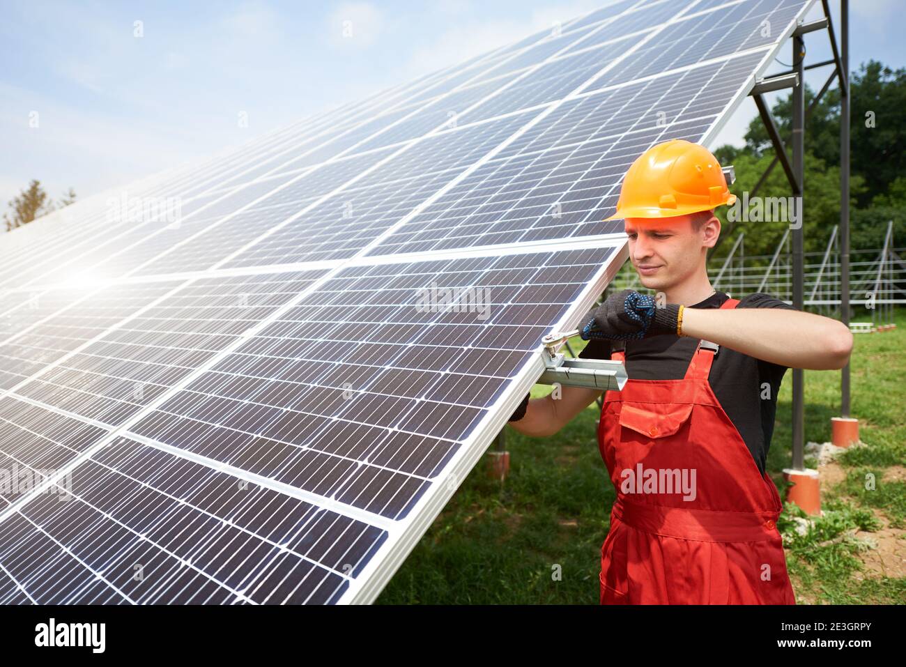 Il tecnico maschile controlla la manutenzione dei pannelli solari. Cappuccio di sicurezza arancione sulla testa. Concetto: Energia rinnovabile, tecnologia, elettricità, servizio, energia verde. Foto Stock