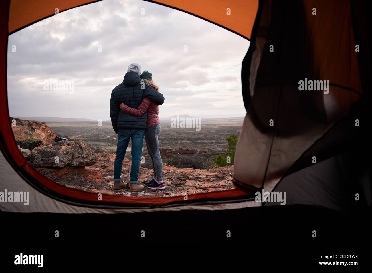Vista posteriore dell'uomo con spalla sulla donna in piedi all'esterno tenda che guarda il cielo e la natura Foto Stock