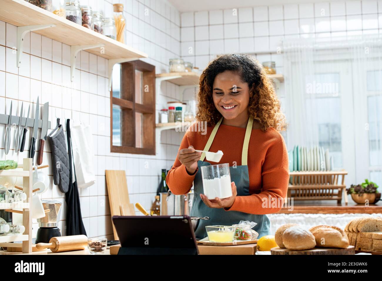 Giovane donna americana Afican imparare online lezione di cucina via tablet computer in cucina a casa Foto Stock