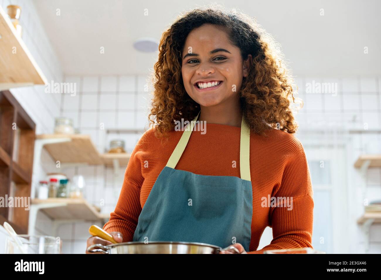 Giovane afroamericana che ama cucinare in cucina durante il soggiorno a casa Foto Stock