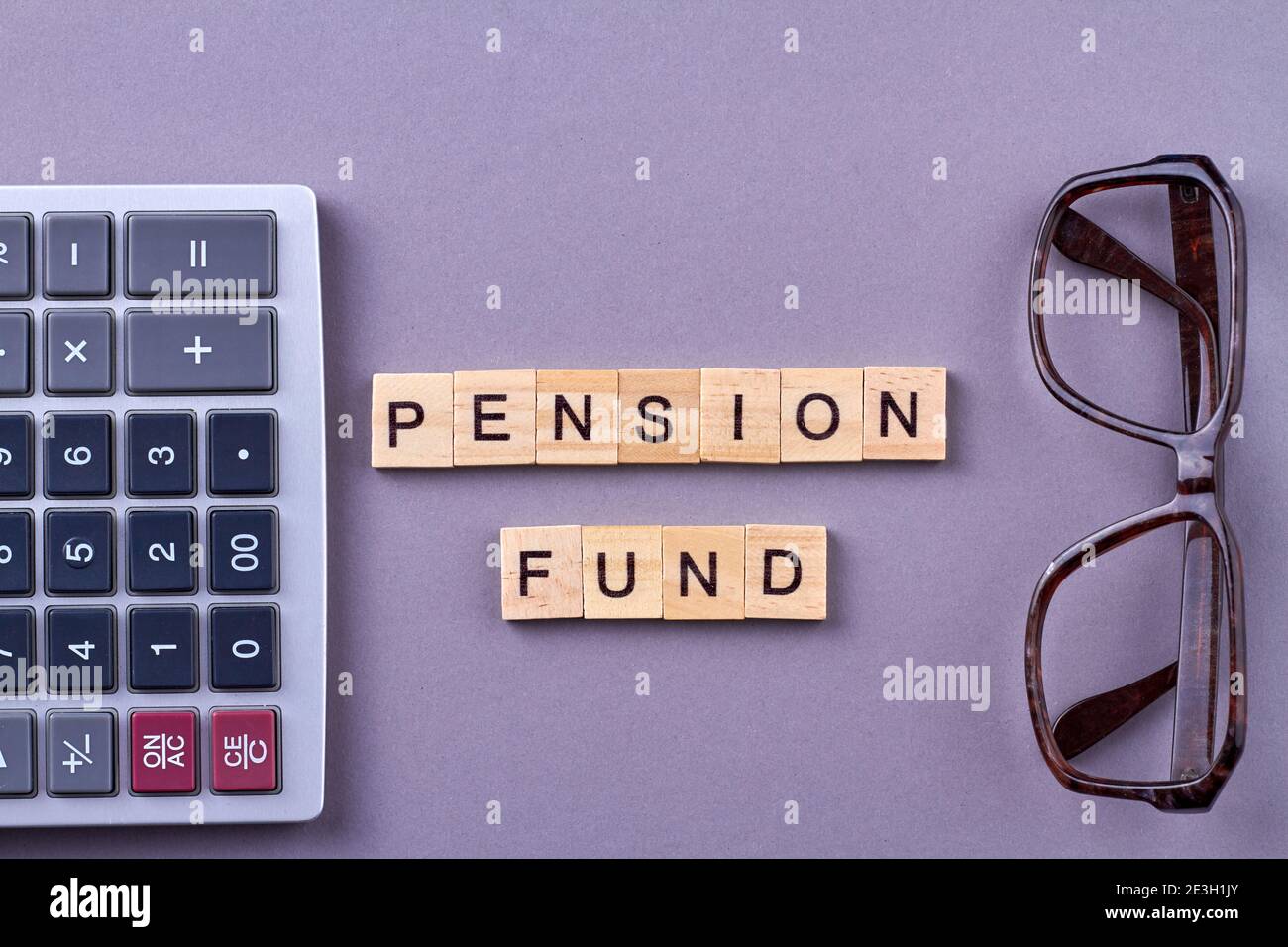 Cassa pensioni con calcolatrice e occhiali sulla scrivania. Foto Stock