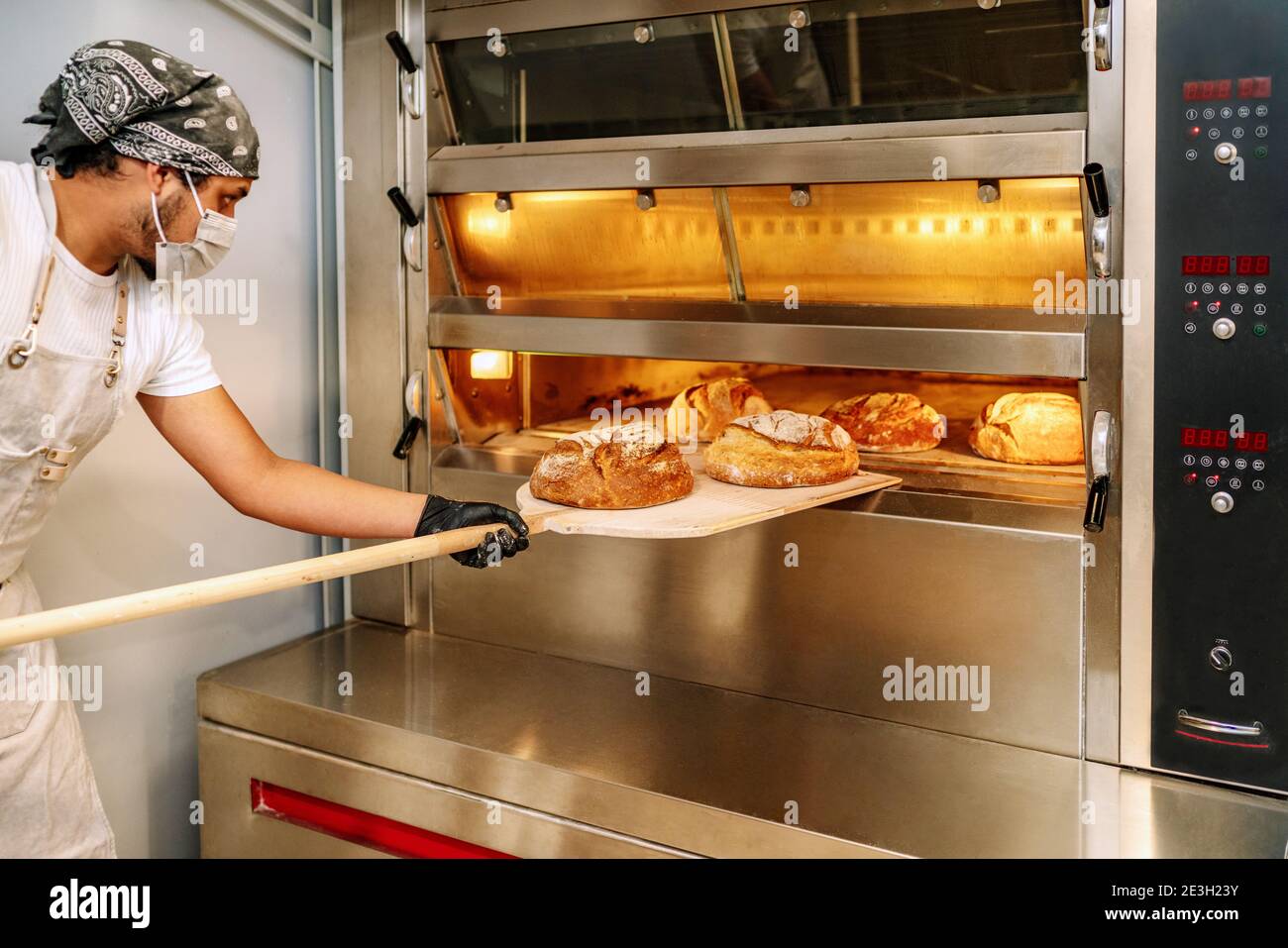 Fuoco selettivo del panettiere latino mettendo il pane nel forno con guanti  e una maschera grazie al 2020 covid19 pandemia di coronavirus Foto stock -  Alamy