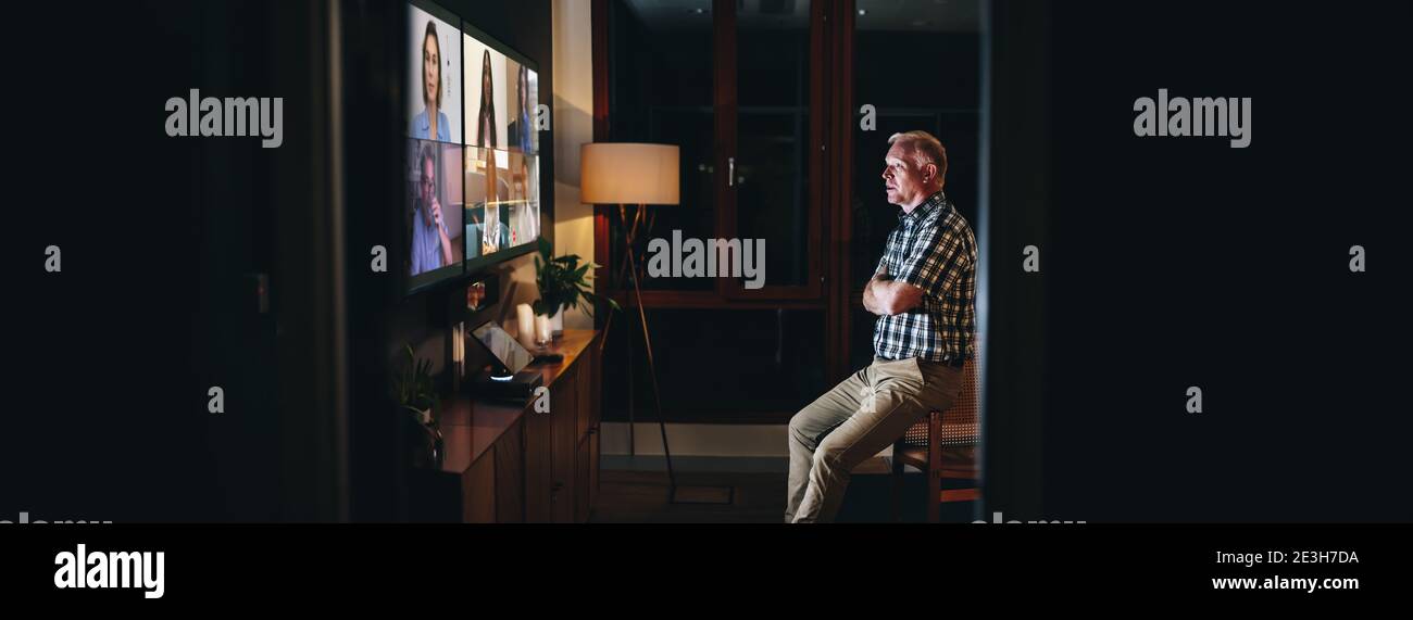 il team aziendale ha una riunione online durante una videochiamata. Uomo seduto in sala riunioni dell'ufficio e impegnato in una videoconferenza con i suoi compagni di squadra di notte. Foto Stock