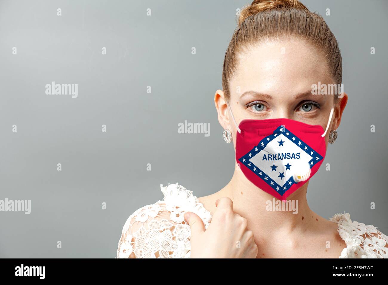 Ritratto di giovane donna che indossa maschera protettiva viso con bandiera Stati Uniti Arkansas per prevenire il coronavirus. Foto Stock