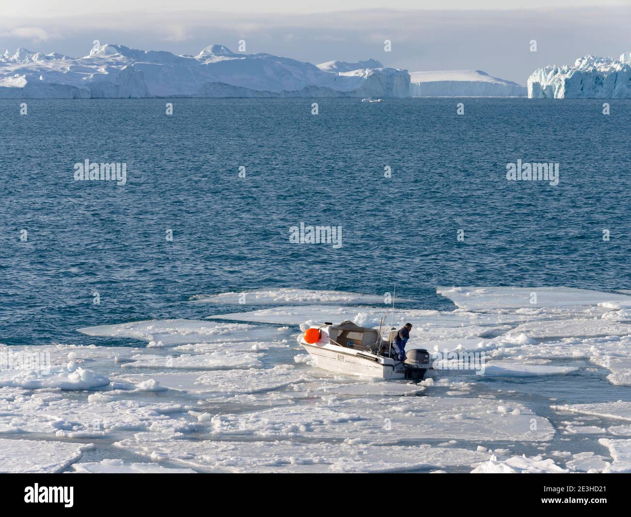 Pescatore pesca nel fiordo. Inverno all'Icefjord Ilulissat, situato nella baia di Disko, nella Groenlandia occidentale, l'Icefjord fa parte del mondo dell'UNESCO Foto Stock