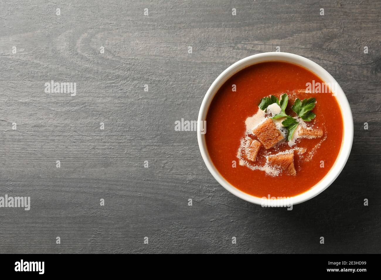 Ciotola di gustosa zuppa di pomodoro su sfondo di legno scuro Foto Stock
