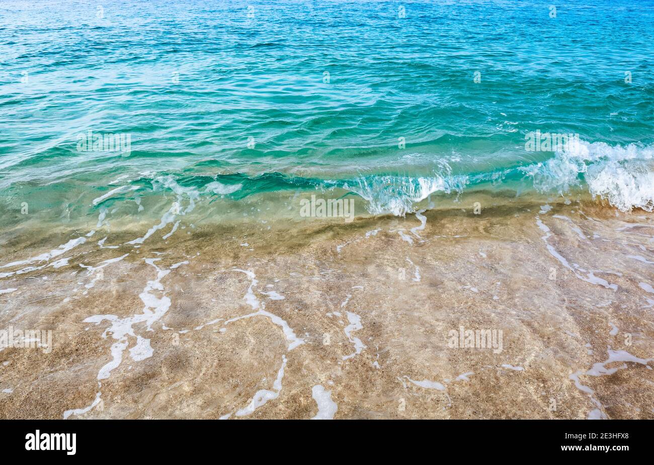 Primo piano di un'onda di acqua cristallina che si frantuma sulla riva di una spiaggia sull'isola di Principe Foto Stock