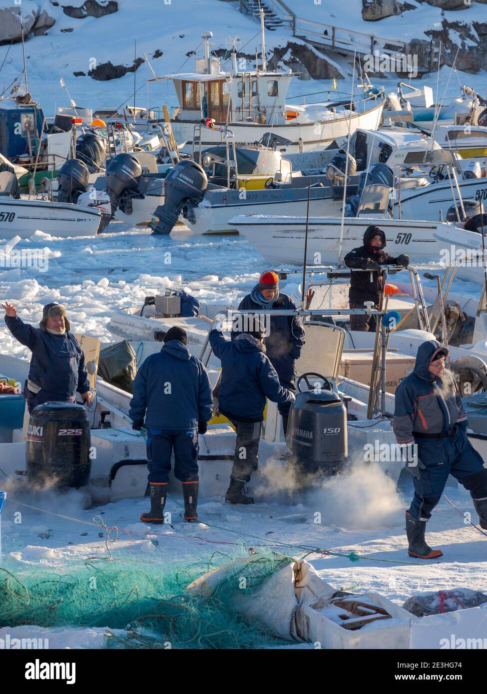 Le piccole imbarcazioni da pesca vengono liberate dal ghiaccio. Inverno nel porto ghiacciato della città Ilulissat sulla riva della baia di Disko. America, Nord America, Greenl Foto Stock