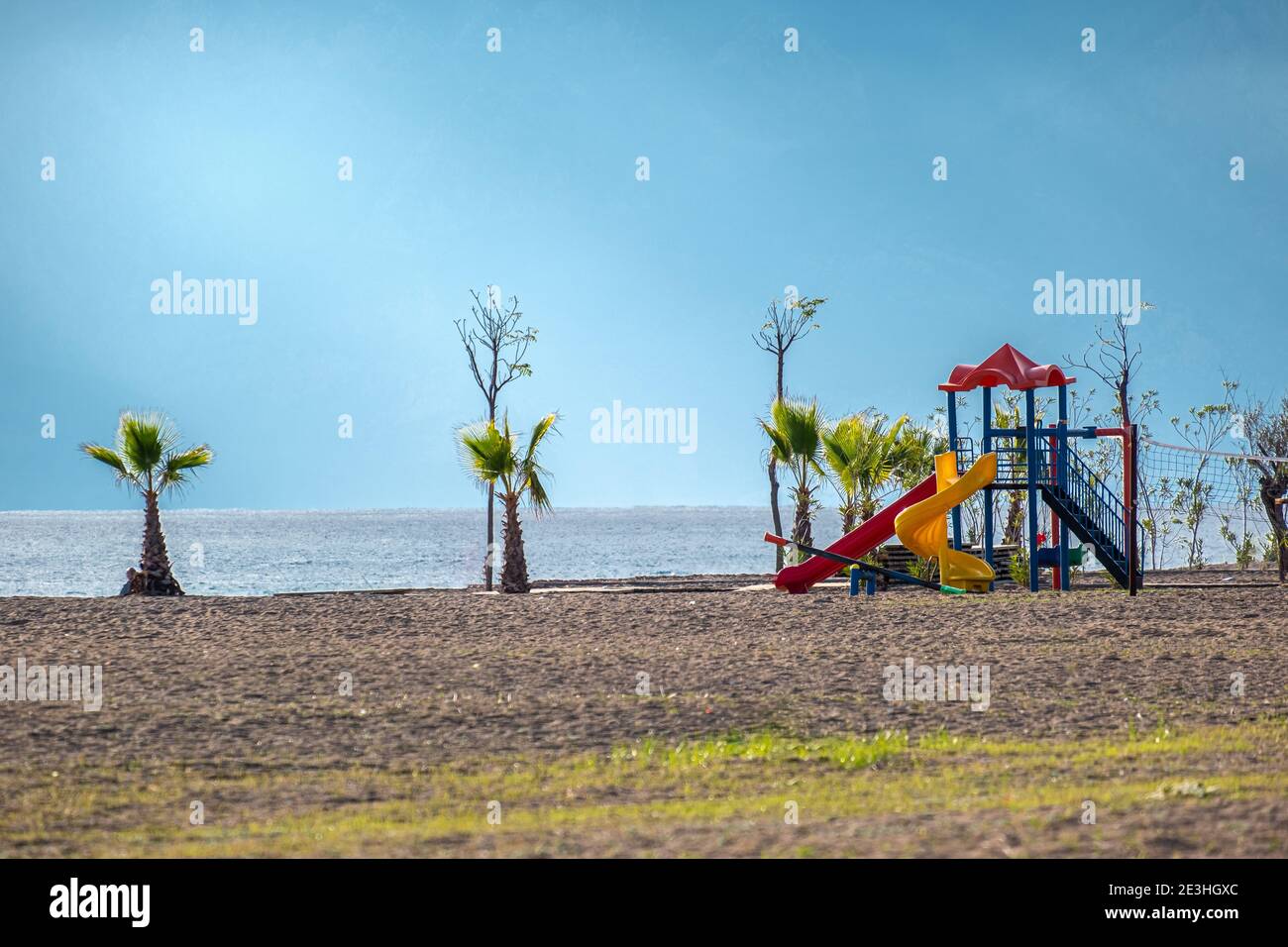 Colorato parco giochi sul cortile nel parco vicino alla spiaggia con cielo limpido e soleggiato Foto Stock