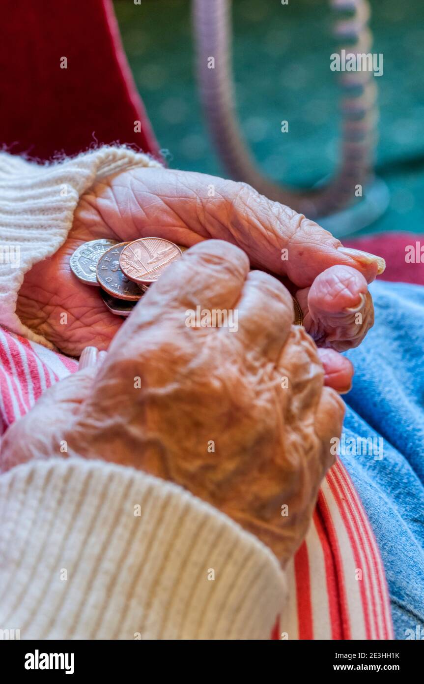 Una signora anziana contando con attenzione i soldi con le monete nelle sue mani. Foto Stock