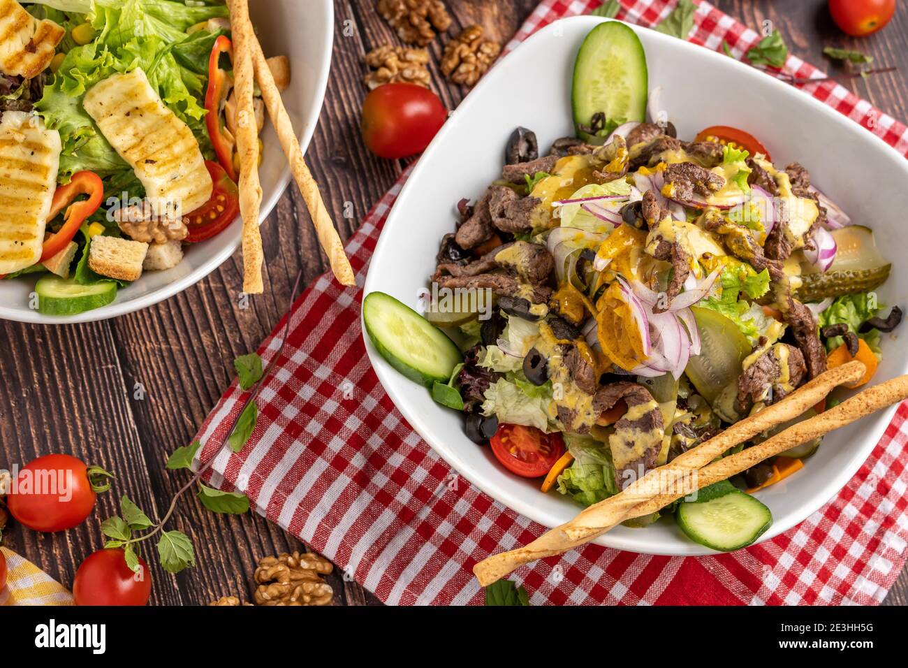 insalata halloumi e insalata di manzo in due piatti separati su sfondo di legno. Foto Stock