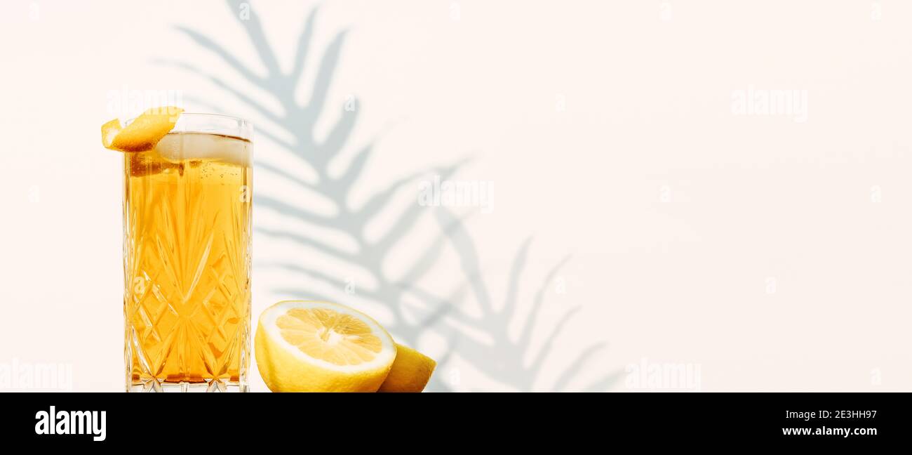 Striscione con un bicchiere di bevanda a base di tè ghiacciato isolato una parete bianca con ombre vegetali Foto Stock