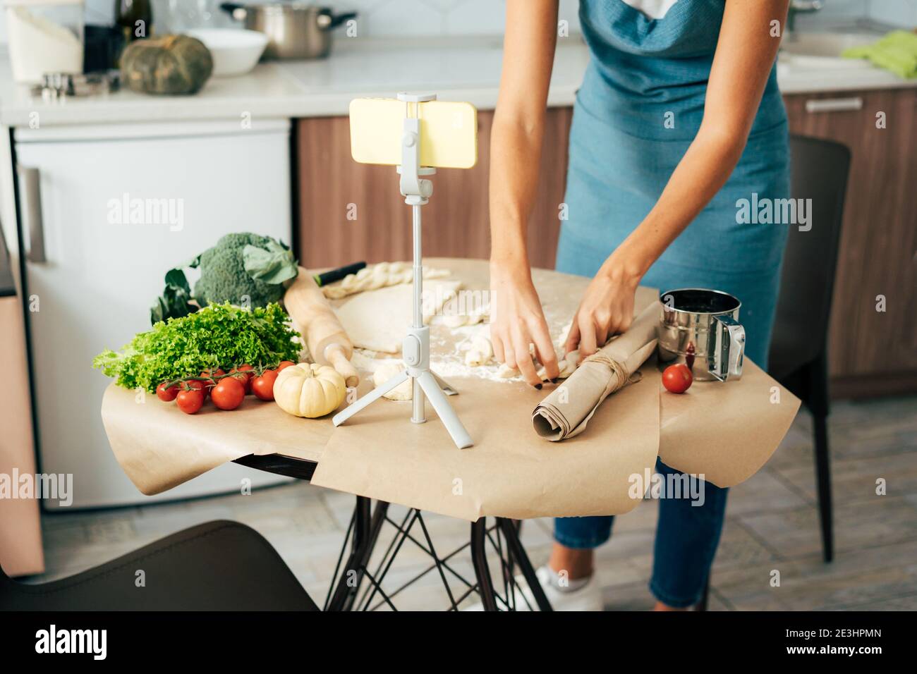 Primo piano di un tavolo da cucina su cui una donna prepara la cena da pasta e verdure. Foto Stock