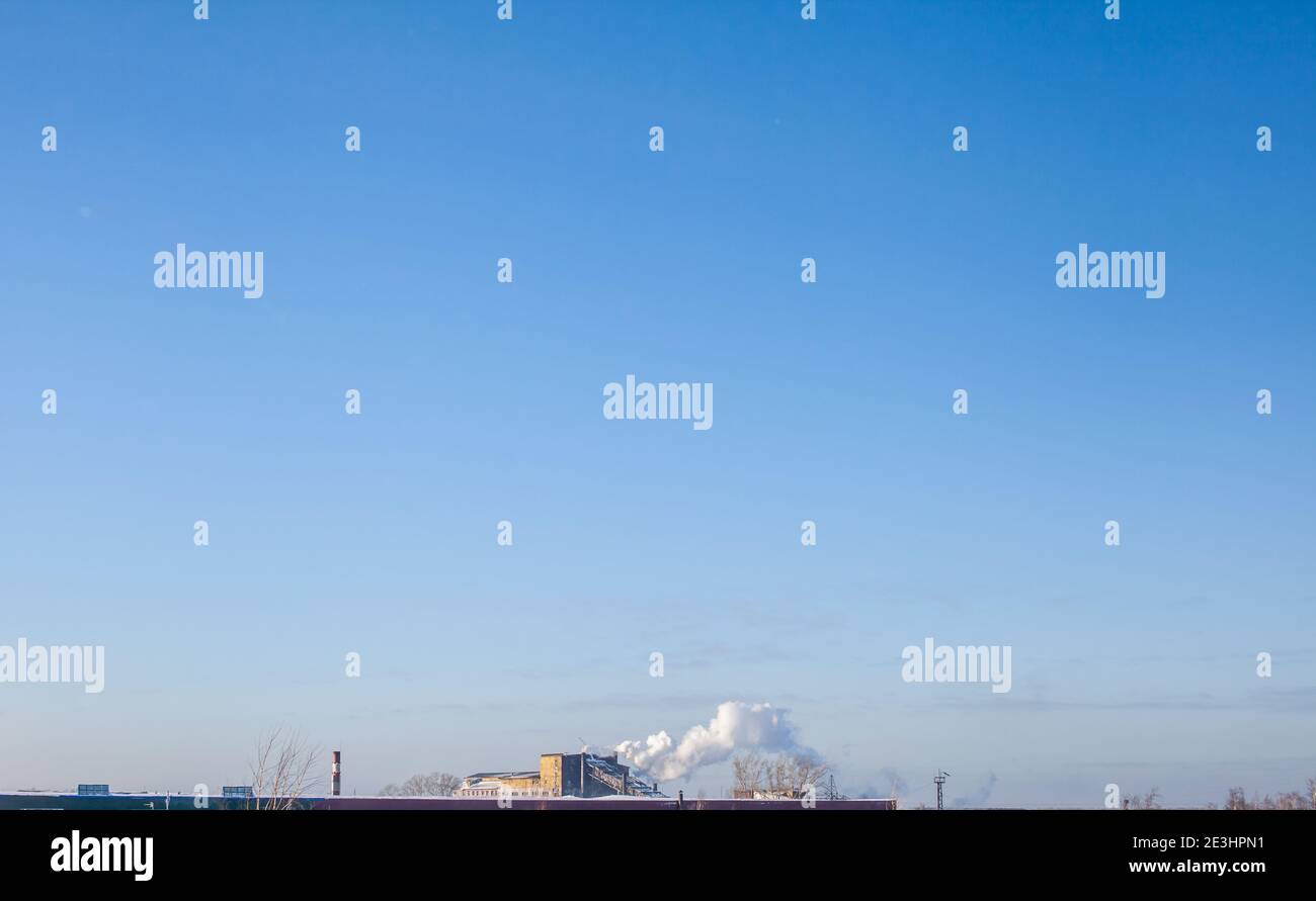 Fumo bianco spesso dal camino del locale caldaia. Fumo contro il cielo blu. Inquinamento atmosferico. Riscaldamento della città. Zona industriale. Foto Stock