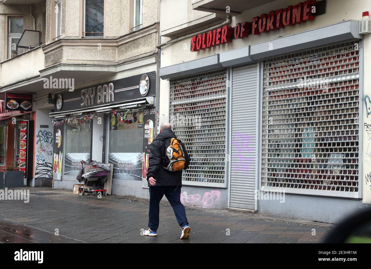 Berlino, Germania. 19 gennaio 2021. Un uomo cammina attraverso diversi negozi chiusi a Frankfurter alle nel quartiere di Prenzlauer Berg. Il governo federale e i primi Stati discuteranno di possibili inasprimenti e ulteriori misure per contenere la pandemia di Corona martedì. Credit: Wolfgang Kumm/dpa/Alamy Live News Foto Stock