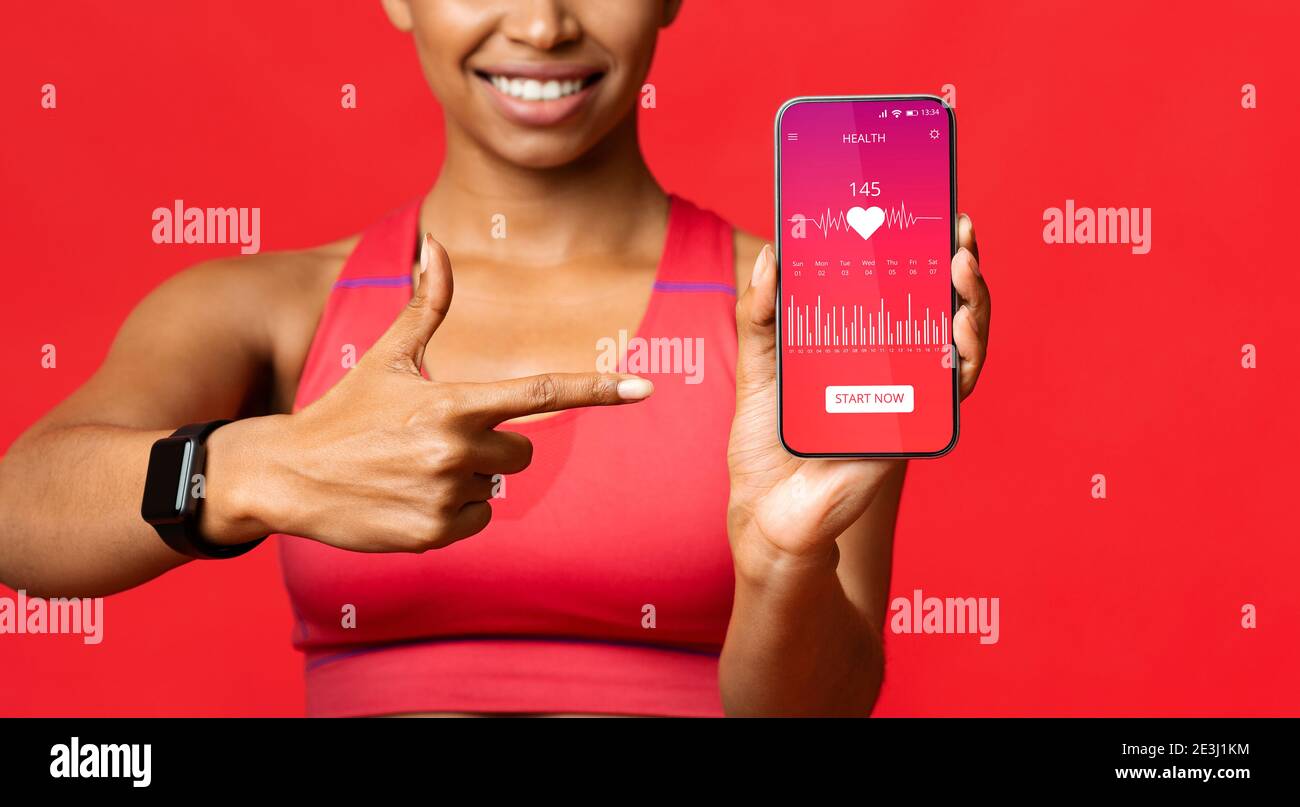 Black Woman che mostra smartphone con l'app Cardio Tracker, sfondo rosso Foto Stock