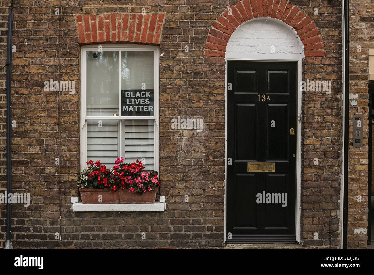Ingresso casa con una porta nera e un segno Black Lives Matter sulla finestra. Qualche strada a Windsor, Berkshire, Inghilterra, Regno Unito. Foto Stock