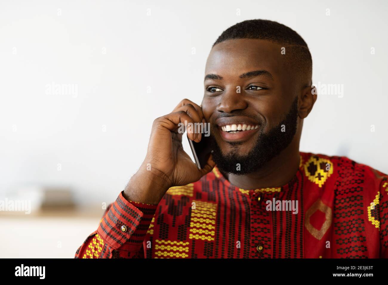 Chiamata cellulare. Sorridente afroamericano Guy in camicia etnica che parla su Cellphone Foto Stock