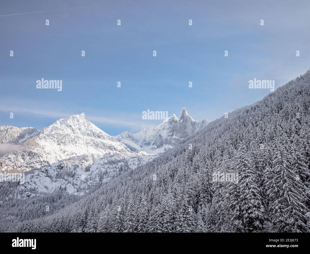 La neve pesante copre le montagne e la treccia di Chamonix in Francia. Uno sciatore di fondo carved un percorso attraverso la neve profonda nella foresta su un perfetto Foto Stock