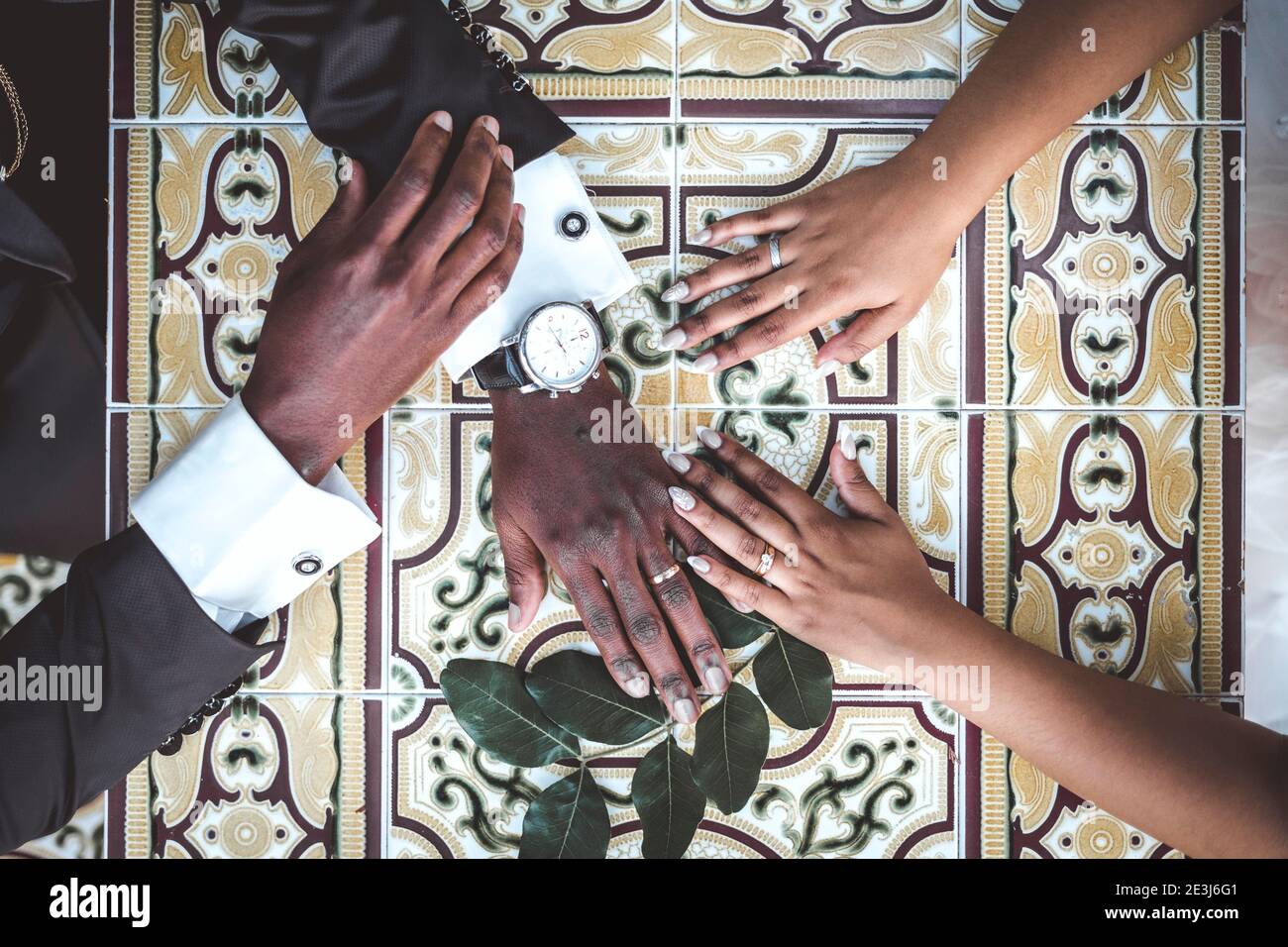 Mani di sposa africana e di sposo con anelli di nozze sopra il tavolo Foto Stock