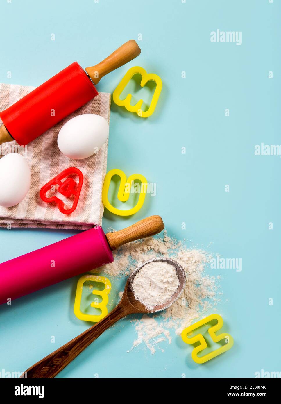 Lezione di cucina per bambini concetto bordo lotto di spazio per il testo. Uova, farina, spille, frese per biscotti a forma di lettera su sfondo azzurro, studio. Foto Stock