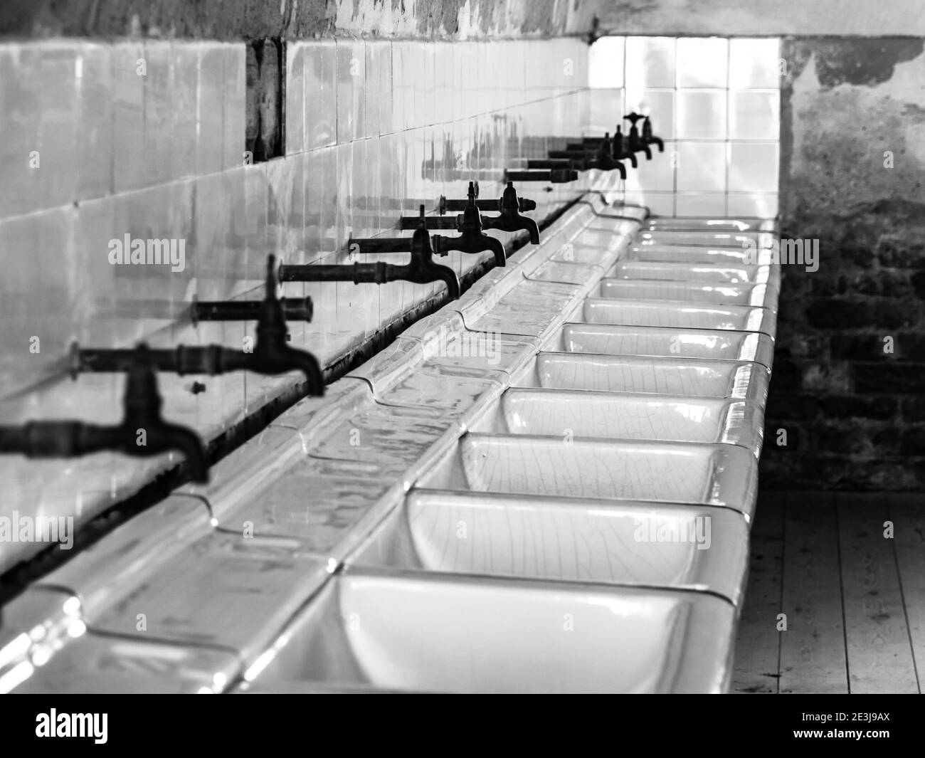 Fila di lavandini e specchi nel vecchio bagno della prigione, immagine in bianco e nero Foto Stock