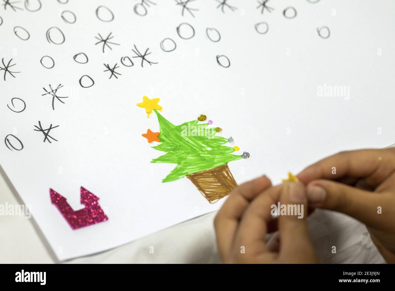 Concorso di disegno natalizio per bambini. Tenendo a mano una stella in paillettes con un disegno raffigurante un castello e un albero di Natale sotto una nuvola di neve Foto Stock