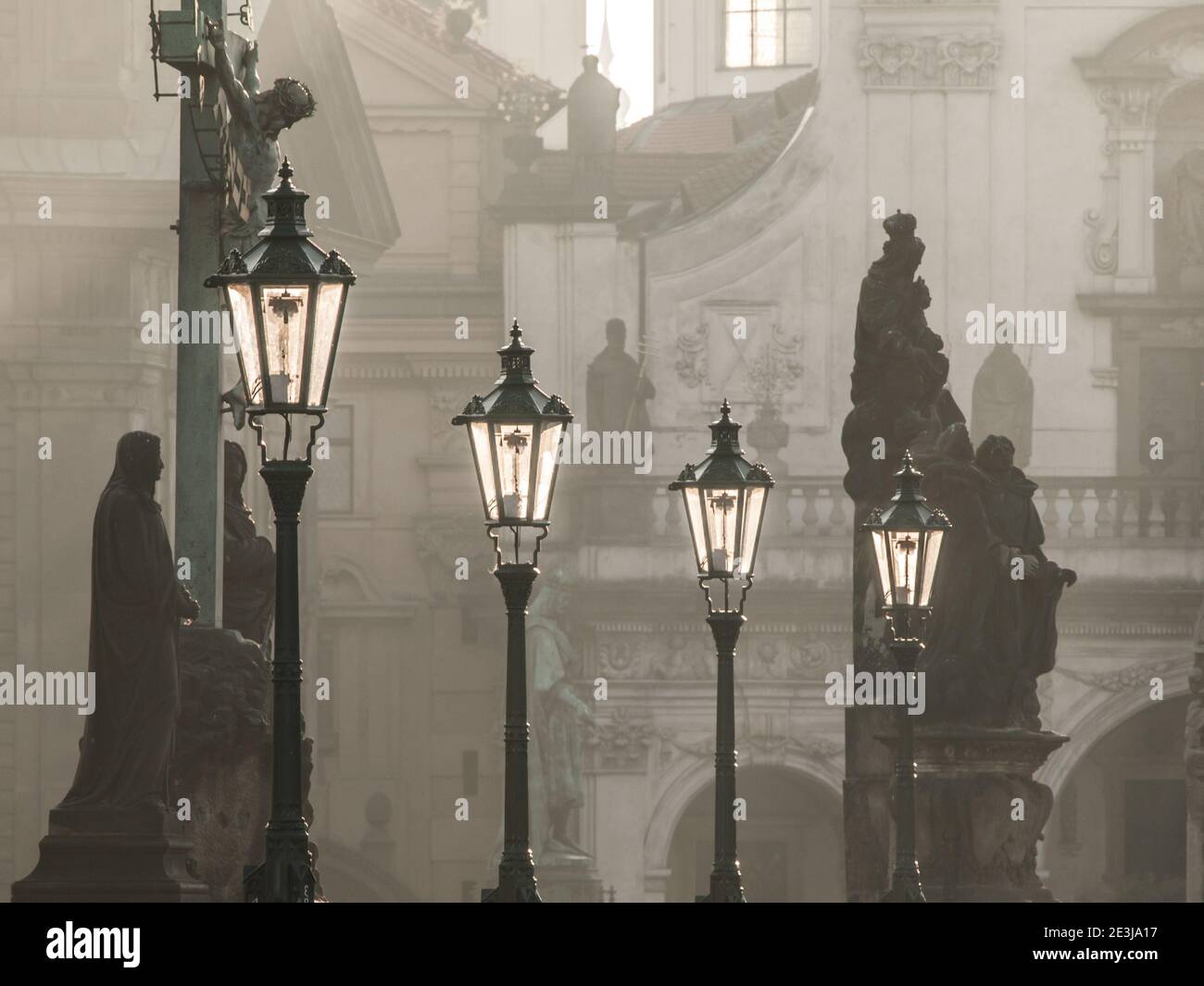 Lampioni di strada sul ponte Carlo illuminati dal sole del mattino e dalle sagome scure delle statue, Praga, Repubblica Ceca Foto Stock