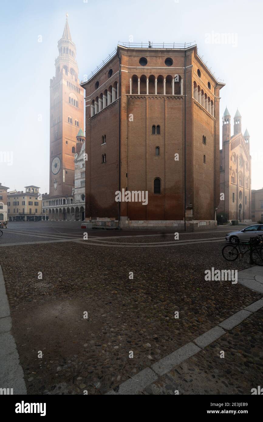 Il battistero romanico di Cremona del XII secolo, con il Duomo medievale e il campanile di Torrazzo sullo sfondo in un giorno di nebbia Foto Stock