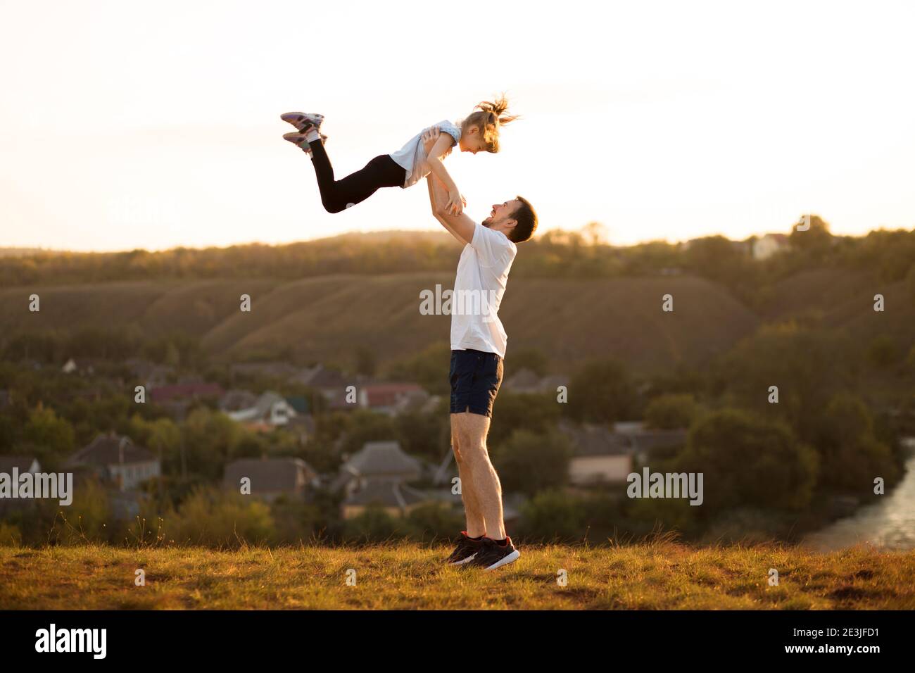 Famiglia attiva. Padre e figlia si divertono insieme. Papà getta sua figlia in cielo Foto Stock