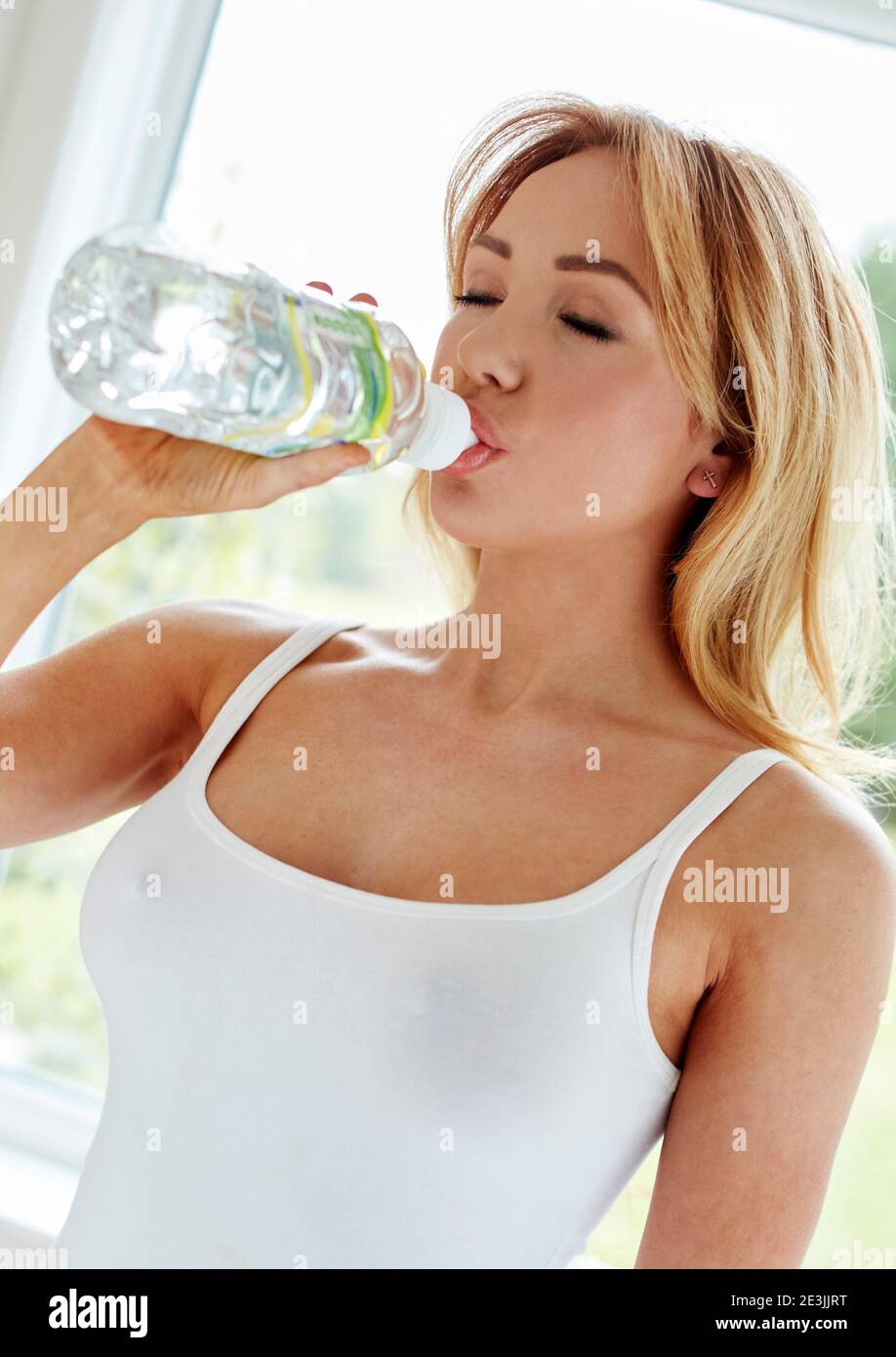 Donna che beve fuori dalla bottiglia di plastica Foto Stock