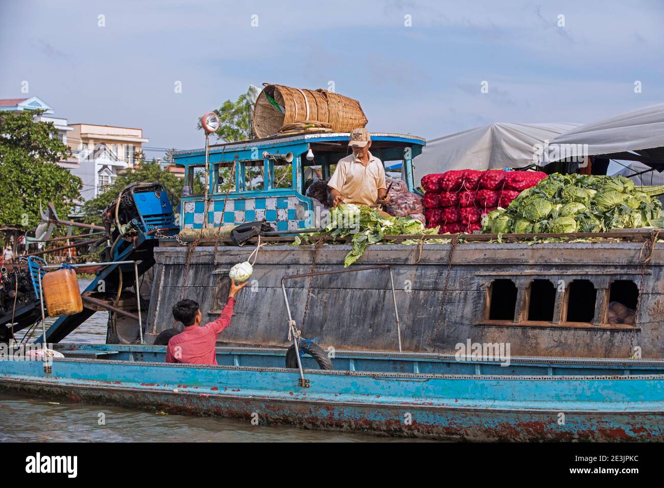 Agricoltore vietnamita che vende verdure da barca tradizionale di legno al mercato galleggiante della città Can Tho nel delta del Mekong, Vietnam Foto Stock