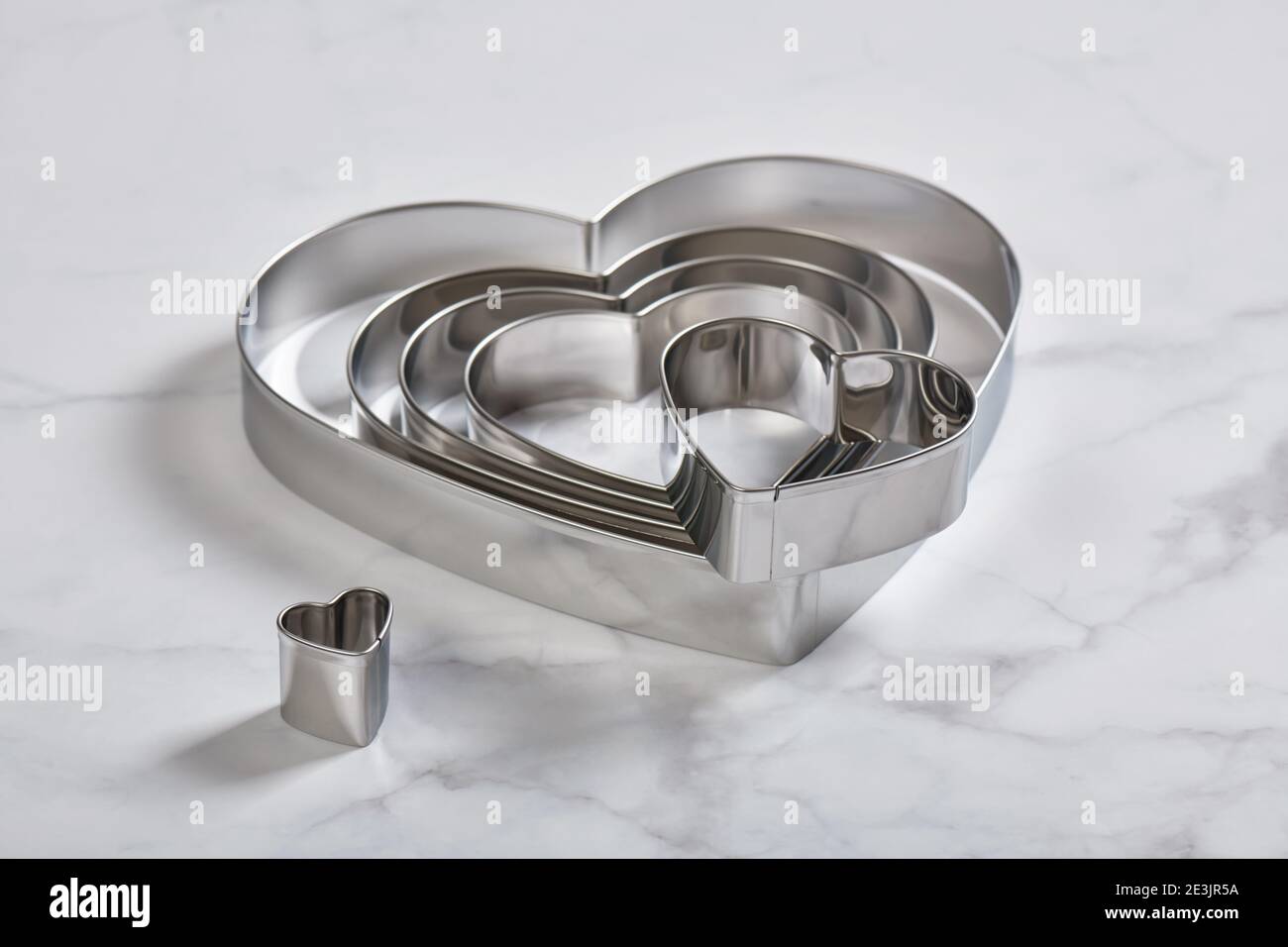 Set di tagliacinette a forma di cuore in acciaio inox su un bianco superficie in marmo Foto Stock