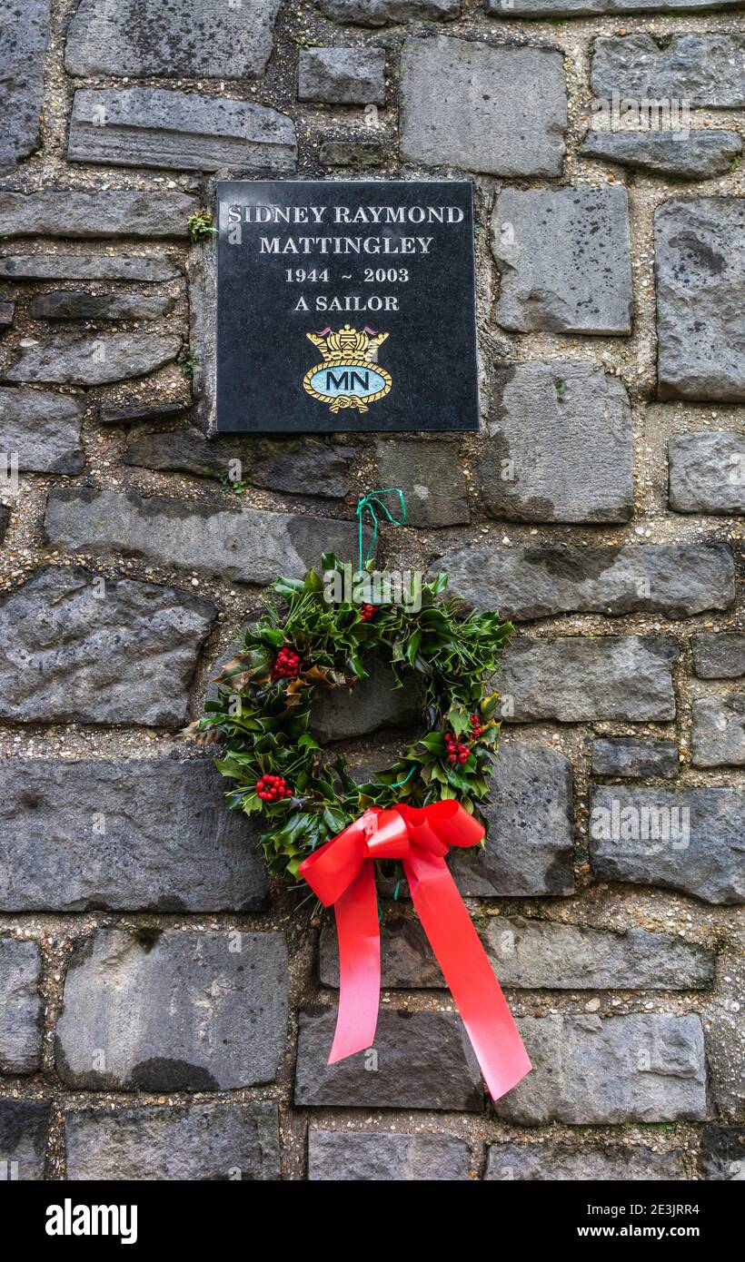 Una corona di Natale appesa sotto un memoriale a Sidney Raymond Mattingley, marinaio della marina mercantile morto nel 2003, Holyrood Church, Southampton, Regno Unito Foto Stock