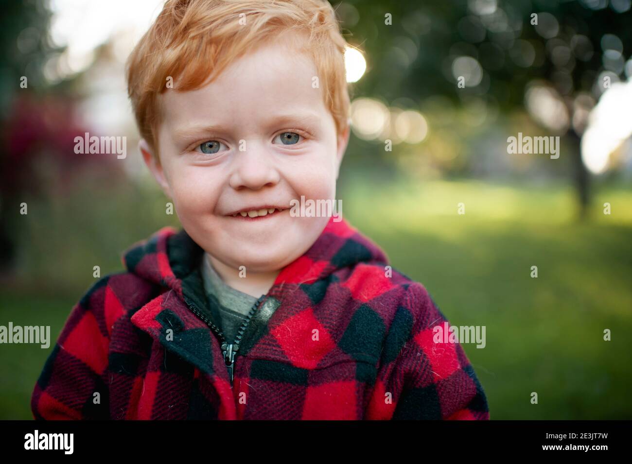 Primo piano del bambino che guarda e sorride all'aperto cappotto invernale Foto Stock