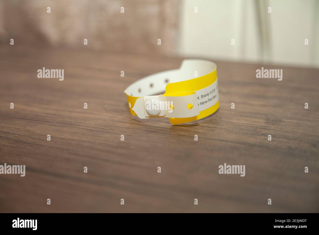 Bracciale giallo dell'ospedale con scrittura sfocata su di esso Foto Stock