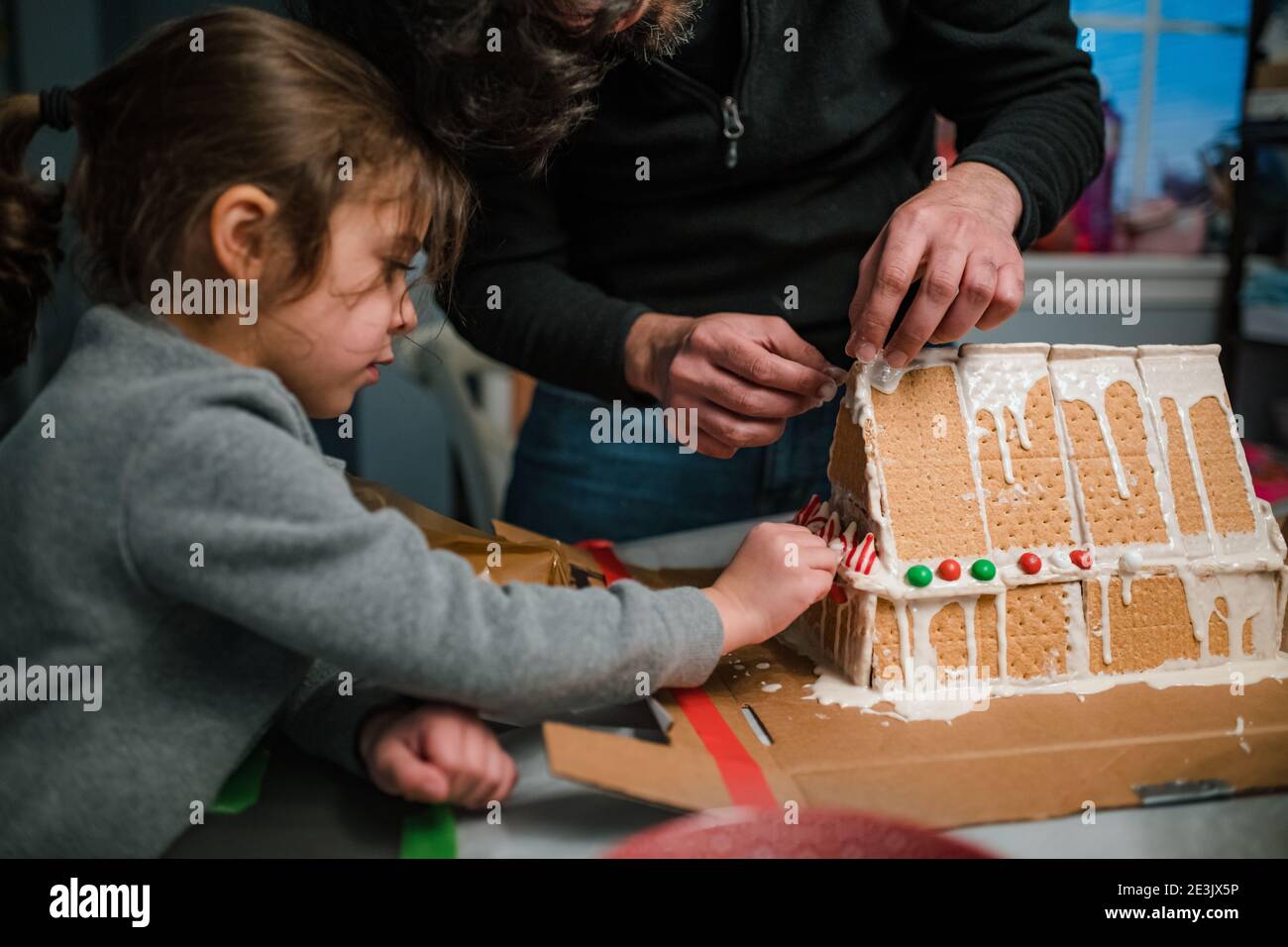 Papà e figlia costruiscono una casa di pan di zenzero in cucina Foto Stock