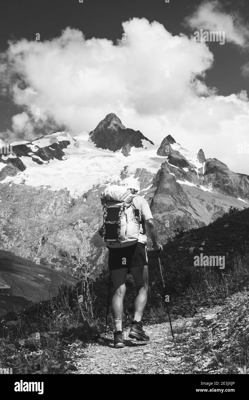 Concetto di benessere per anziani. Uomo anziano trekking Alpi francesi in estate con zaino solare. Aiguille des Glaciers, Monte Bianco. Vista da Chapieu Foto Stock