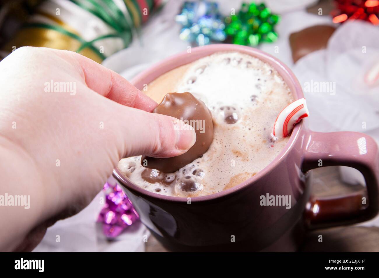 Tuffando le caramelle di cioccolato in cacao caldo con i marshmallows e una canna di caramella rotta, vicino al nastro di avvolgimento, porpora, blu, verde e archi rossi e tre Foto Stock