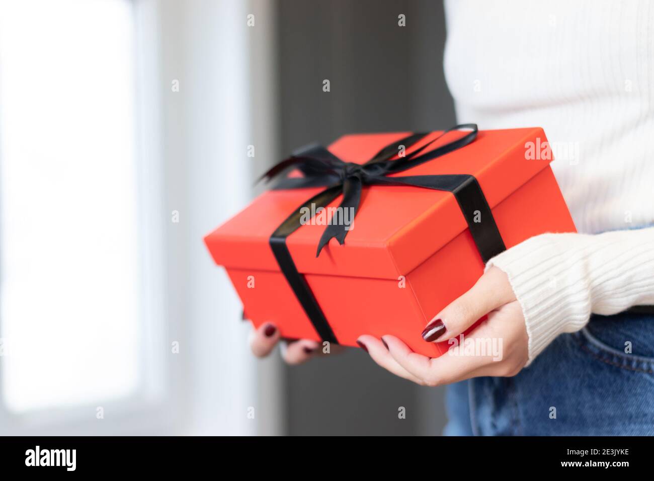 Una donna che tiene una scatola regalo rossa tra le sue mani. Buon giorno  di San Valentino, colore rosso, icona del cuore, sfondo isolato Foto stock  - Alamy