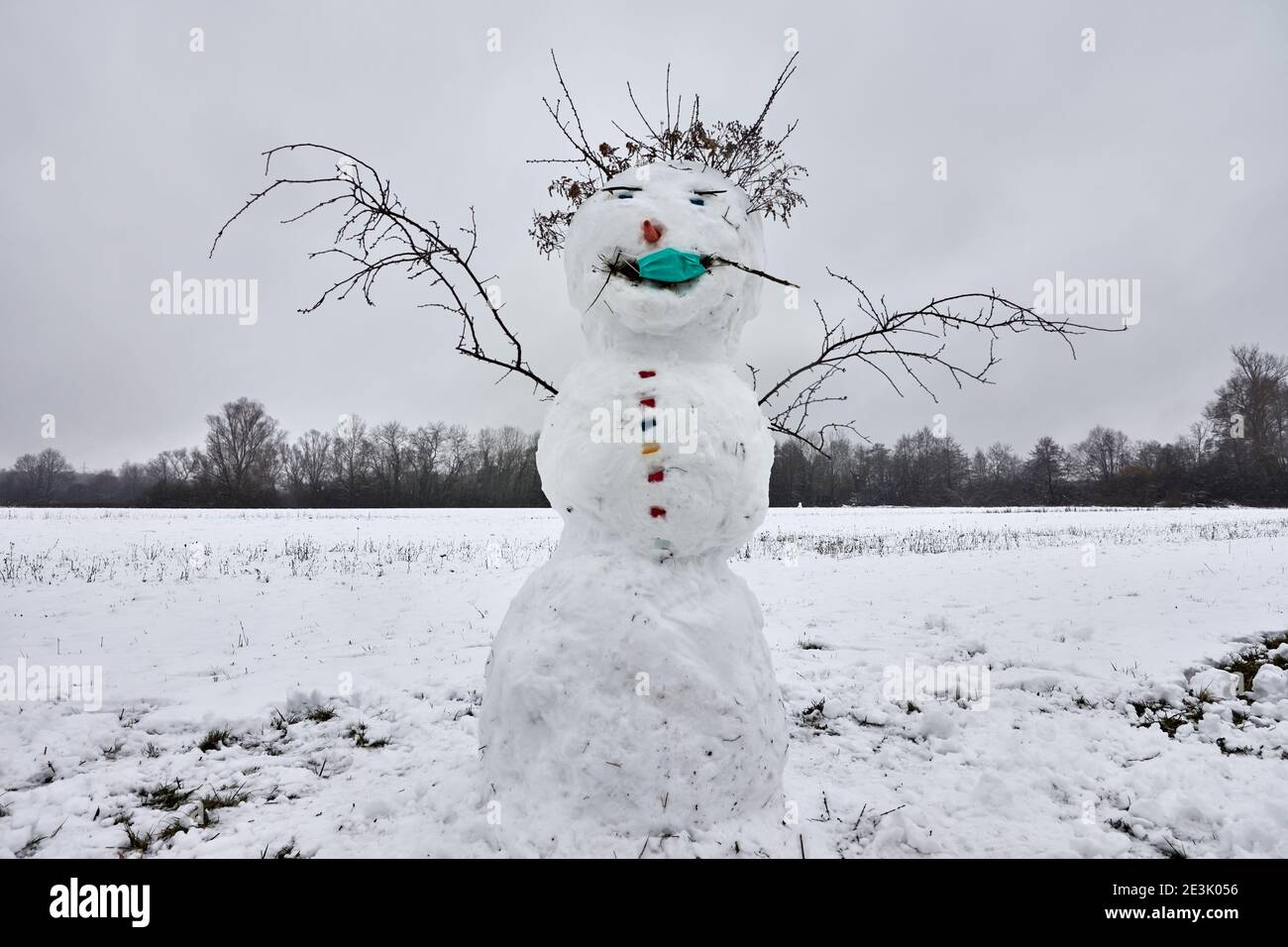 Pupazzo di neve in paesaggio invernale con una maschera facciale per la protezione e il contenimento del coronavirus, Covid-19 Foto Stock
