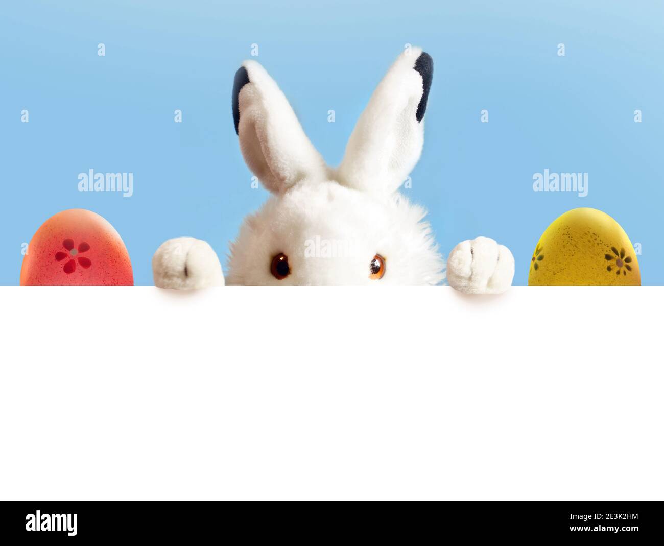 Un coniglio bianco di Pasqua giocattolo sono due uova di colore pasquale su sfondo blu e bianco. Foto Stock