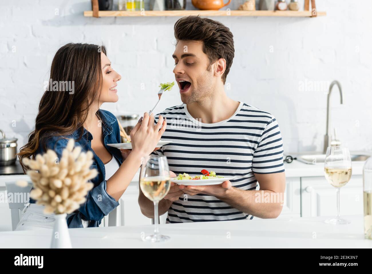 felice donna che tiene piatto e che alimenta il ragazzo con la lattuga Foto Stock