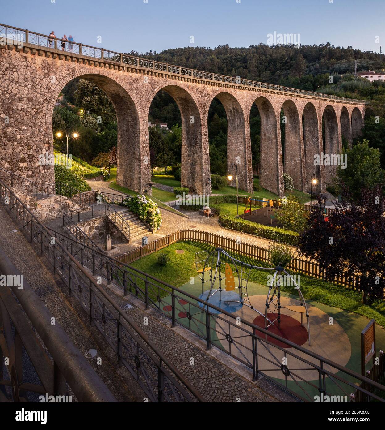 Paesaggio del Parque da Liberdade a Vouzela, Portogallo, con il vecchio ponte ferroviario evidenziato e il parco giochi in primo piano. Foto Stock