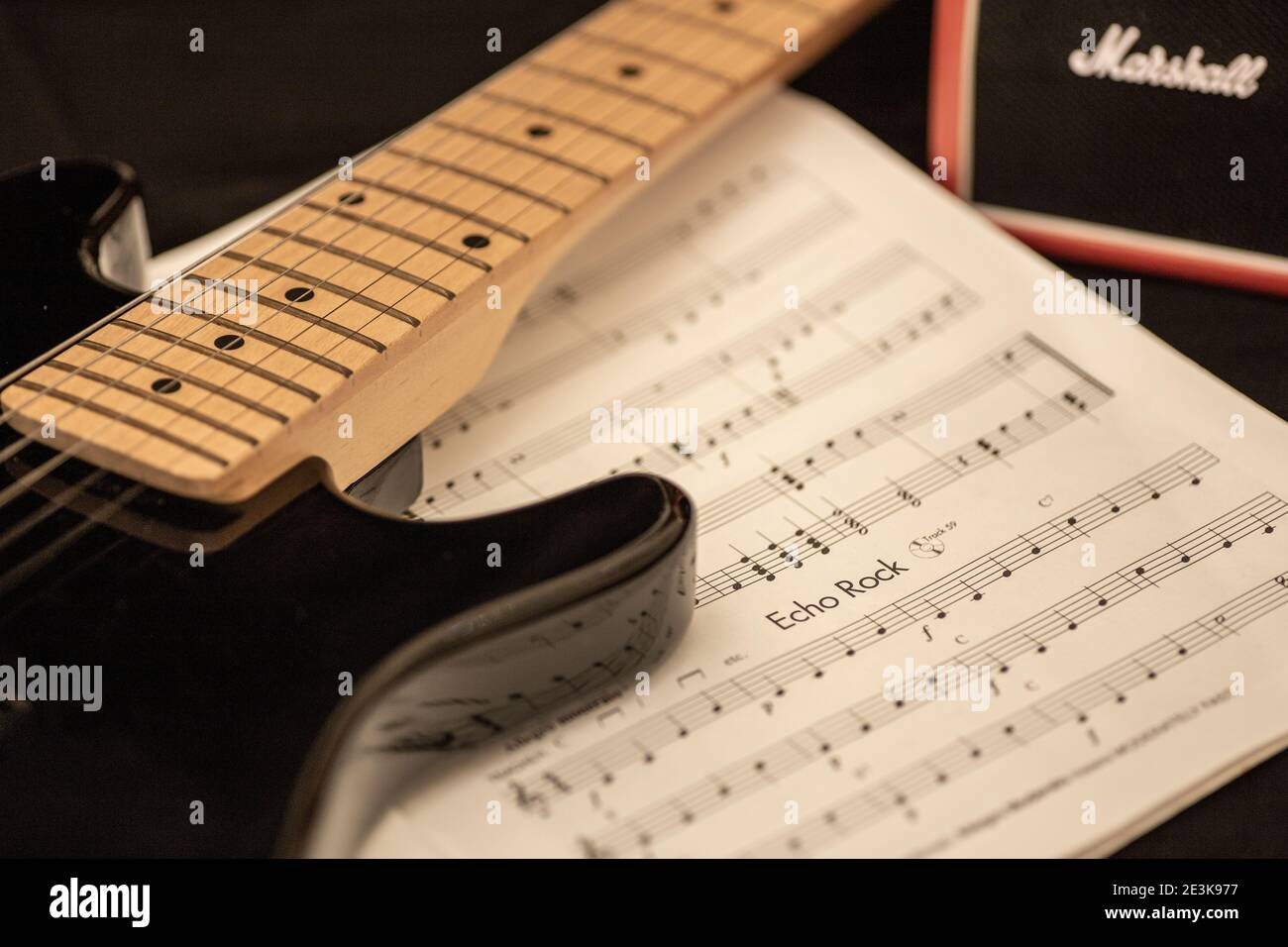 Closeup di chitarra elettrica e libro di musica con un amplificatore Marshall in background. Esercitarsi, comporre o produrre musica rock. Foto Stock