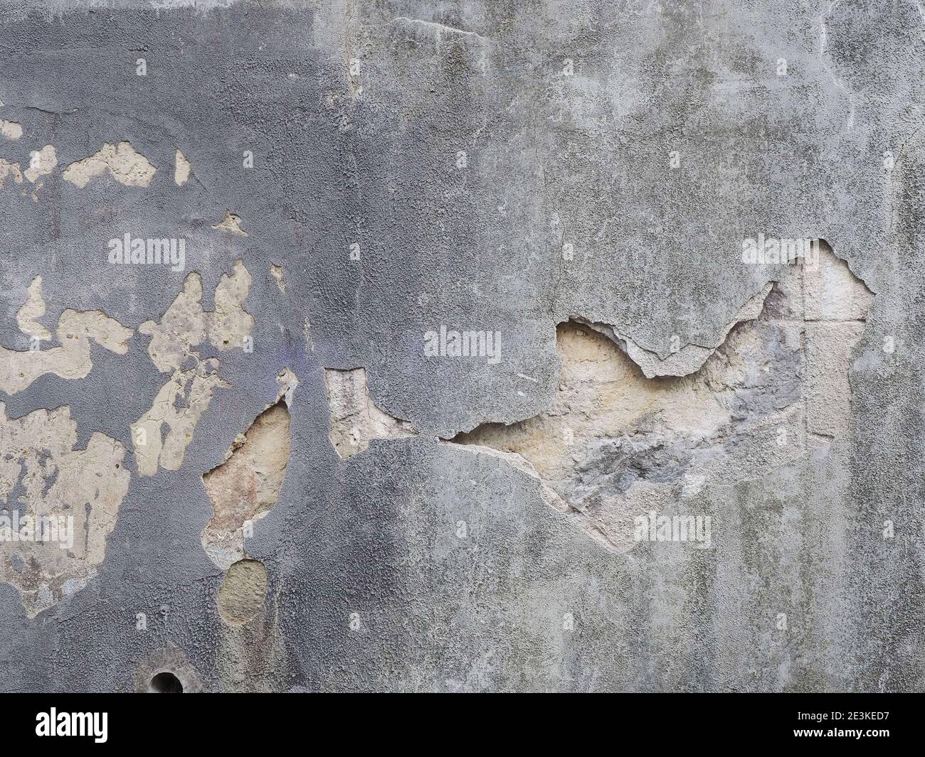 Muro di cemento con pezzo di intonaco che è caduto e piccoli punti di peeling Foto Stock
