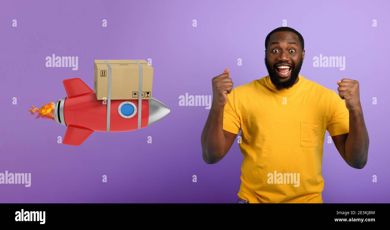 Black man è felice di ricevere un pacchetto. Concetto di consegna rapida come un razzo. Sfondo viola Foto Stock