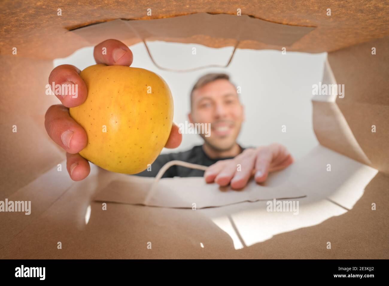 Uomo che prende la mela dalla borsa di carta della spesa. Consegna a domicilio dal negozio di alimentari Foto Stock