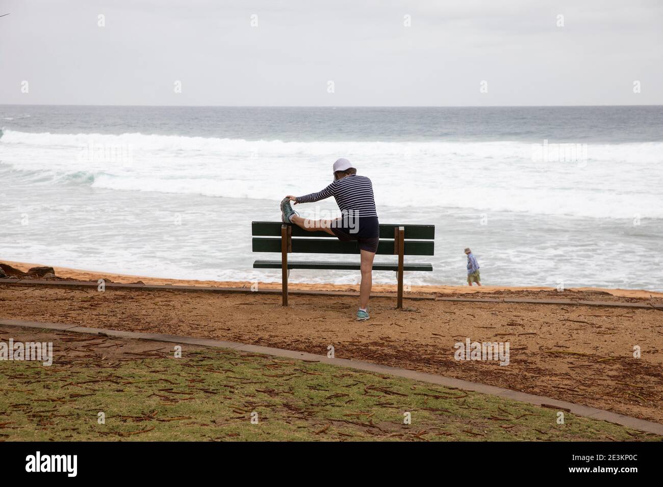 Donna australiana di mezza età che fa il fitness e l'esercizio fisico compreso gamba Si estende su una spiaggia di Sydney, NSW, Australia Foto Stock