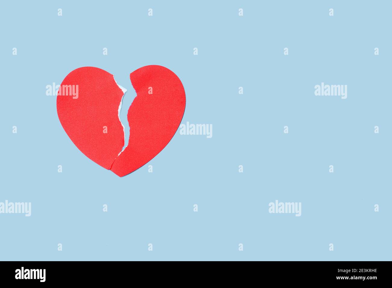 Primo piano carta rossa cuore rotto su sfondo blu. San Valentino e concetto di depressione Foto Stock
